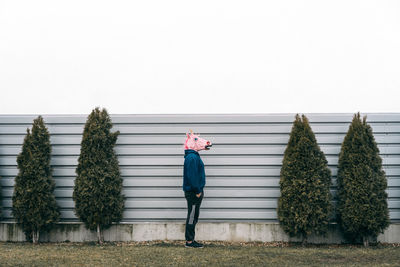 Side view of man wearing mask by wall