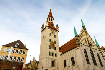Low angle view of clock tower amidst buildings against sky