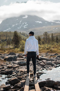 Rear view of man with camera standing on rocks