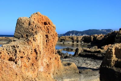 Rock formations on beach against clear blue sky