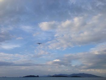 Airplane flying over sea against sky