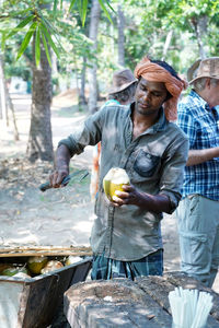 Full length of man holding ice cream standing against trees