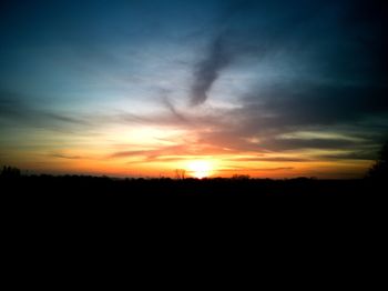 Silhouette landscape against dramatic sky during sunset