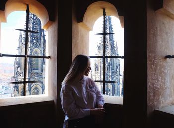 Woman looking through window at home