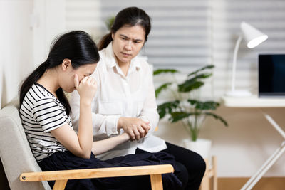 Side view of young woman using mobile phone while sitting at home