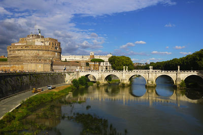 Bridge over river in city against sky