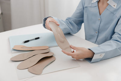 Midsection of doctor holding book on table