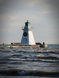 Lighthouse by sea against sky