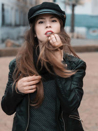 Portrait of beautiful young woman wearing hat standing outdoors