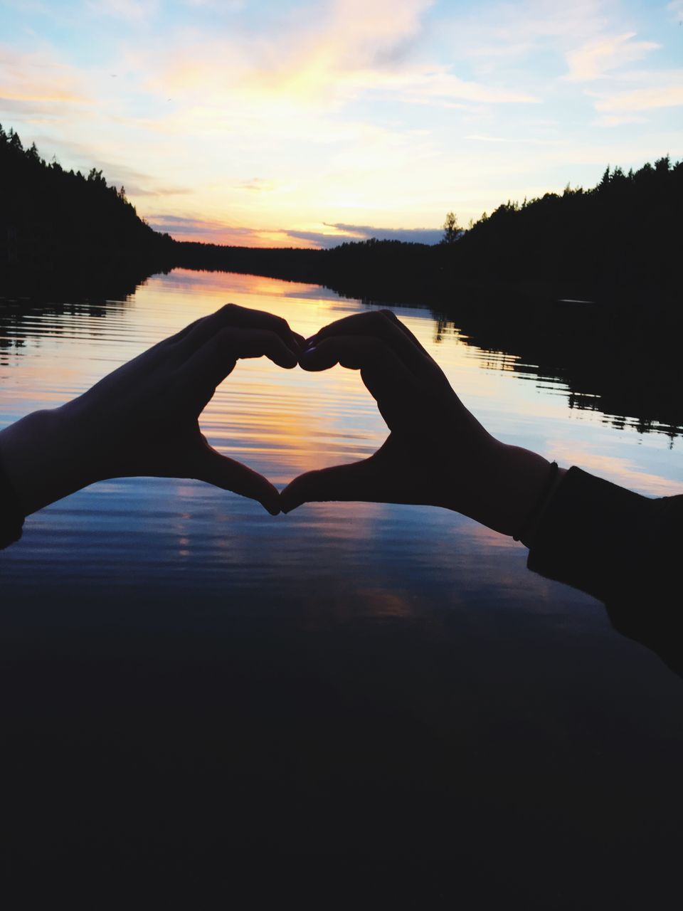 heart shape, sunset, love, water, sky, human hand, silhouette, nature, human body part, scenics, cloud - sky, beauty in nature, reflection, tranquility, forming, tranquil scene, outdoors, lake, one person, close-up, day, people