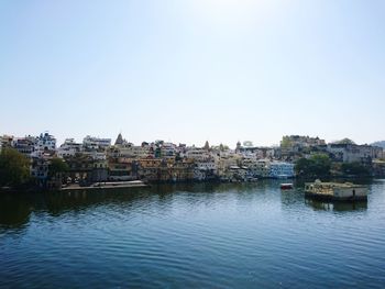 Buildings by river against clear sky