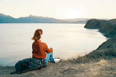 Woman sitting on land against sky