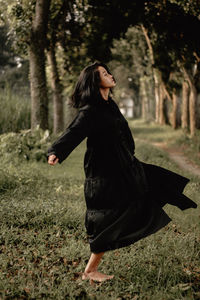 Side view of young woman standing on field