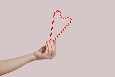 Cropped hand of woman holding heart shape against white background