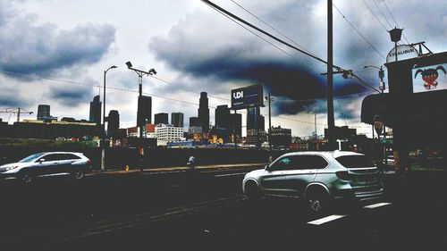 Cars on road in city against sky