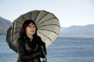 Portrait of young woman standing on mountain against clear sky