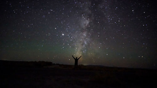 Silhouette woman standing on field against sky at night