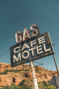 Low angle view of road sign against clear blue sky