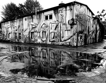 Graffiti on old building by canal against sky