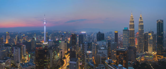 Illuminated buildings in city against sky