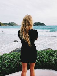 Rear view of woman standing at beach