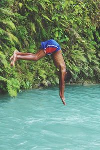 Full length of shirtless man jumping in water