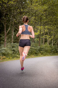 Full length rear view of woman walking on road