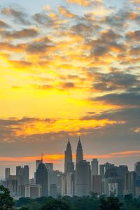 Buildings in city against cloudy sky during sunset