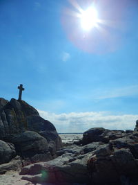 Low angle view of cross on rock on sunny day at beach