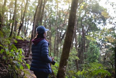 Woman standing amidst trees in forest