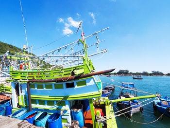 Fishing boat moored in sea against blue sky