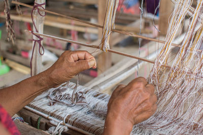 Close-up of worker holding thread while working on handloom