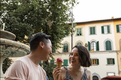 Diverse couple laughing with gelato in italian piazza