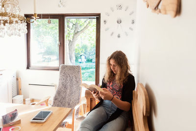 Teenage girl reading book while sitting on sofa