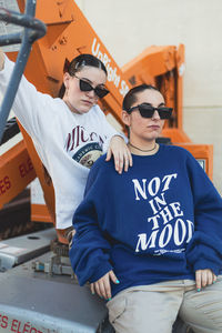 Portrait of young woman wearing sunglasses while sitting outdoors