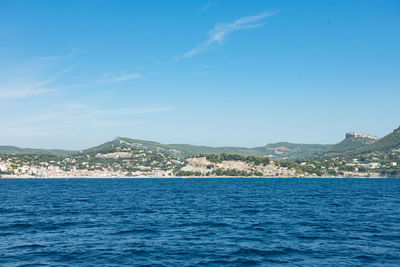 Scenic view of sea by townscape against sky