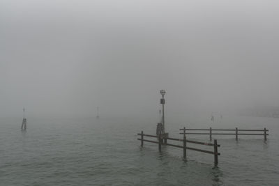 Wooden posts in sea against sky