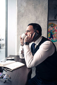 Man using mobile phone while sitting on table