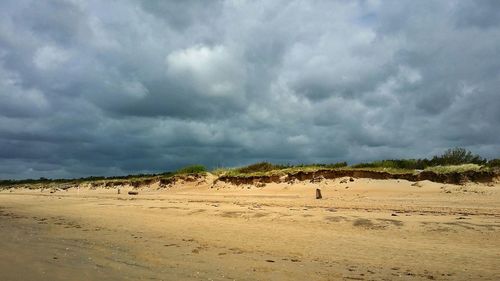 Scenic view of beach against cloudy sky