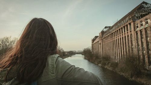 Rear view of woman with umbrella against sky