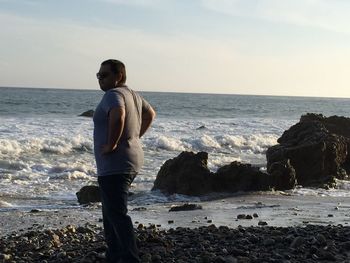 Rear view of man looking at sea against sky