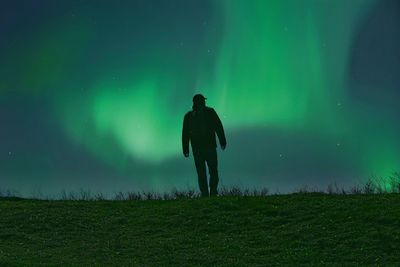 Rear view of man standing on land against sky at night