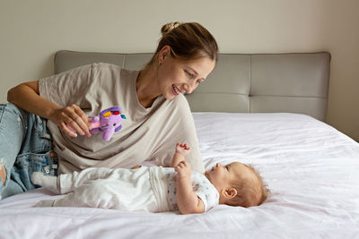 Boy playing with teddy bear on bed at home