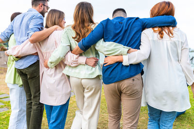 Rear view of friends standing against people