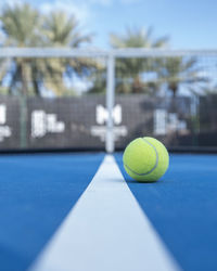 Close-up of yellow tennis ball on blue court