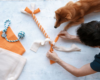 Top view of adult man making diy homemade educational toys for dogs using fleece fabric stripes