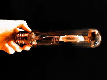 Close-up of hand holding candles against black background