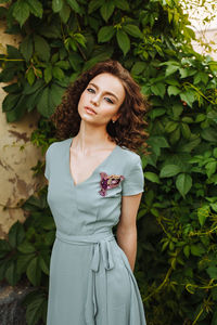 Portrait of young woman wearing make-up while standing against plants