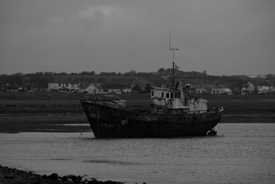 Boat moored on beach against sky