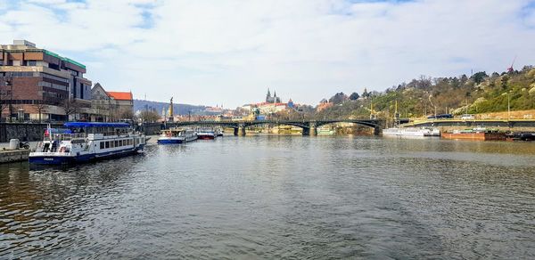 Bridge over river by buildings in city against sky